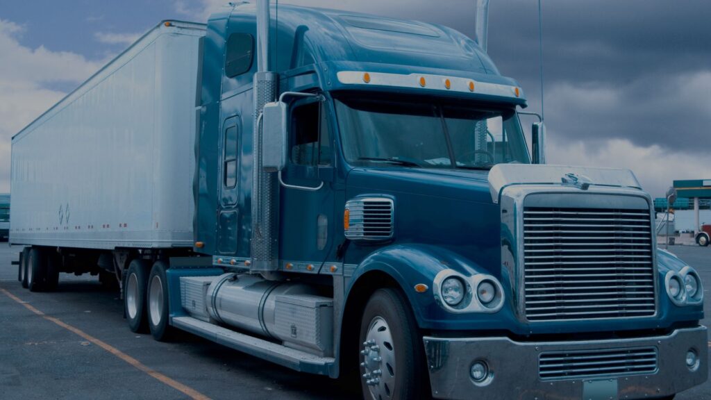 A blue truck is driving down the street.