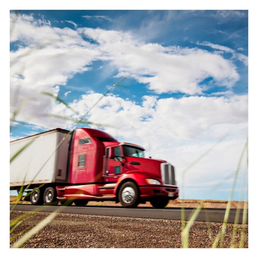 A red truck is driving down the road.