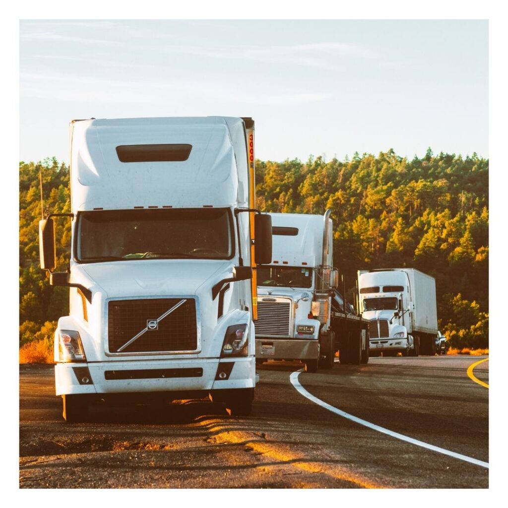 A group of semi trucks driving down the road.