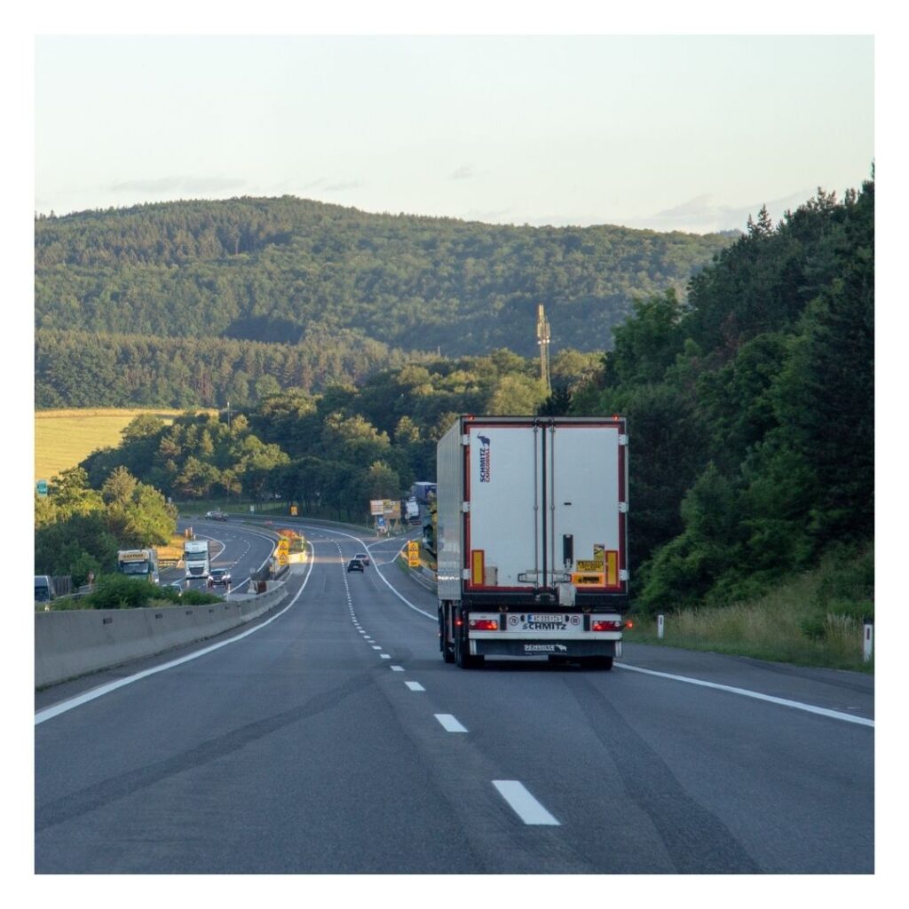 A truck driving down the road near some trees.