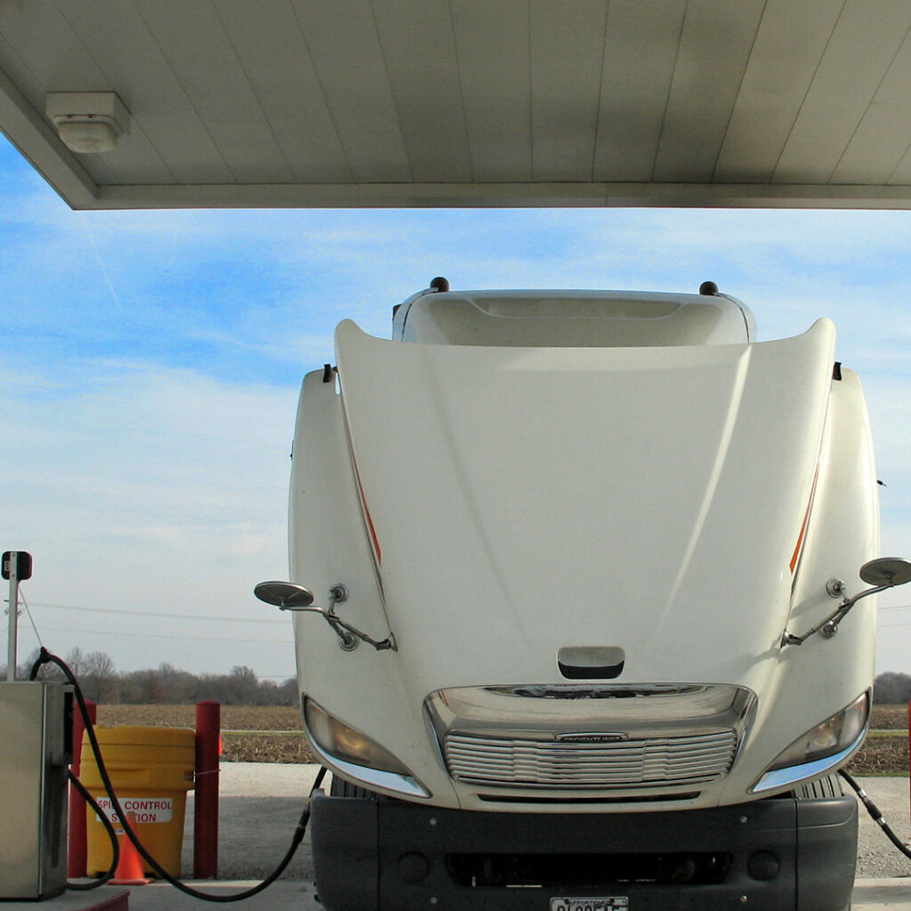 A white truck is parked at the gas station.